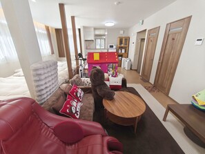 Ein Hotelzimmer mit einem roten Ledersofa, einem Holztisch, einem Teddybären und einem Spielzelt.