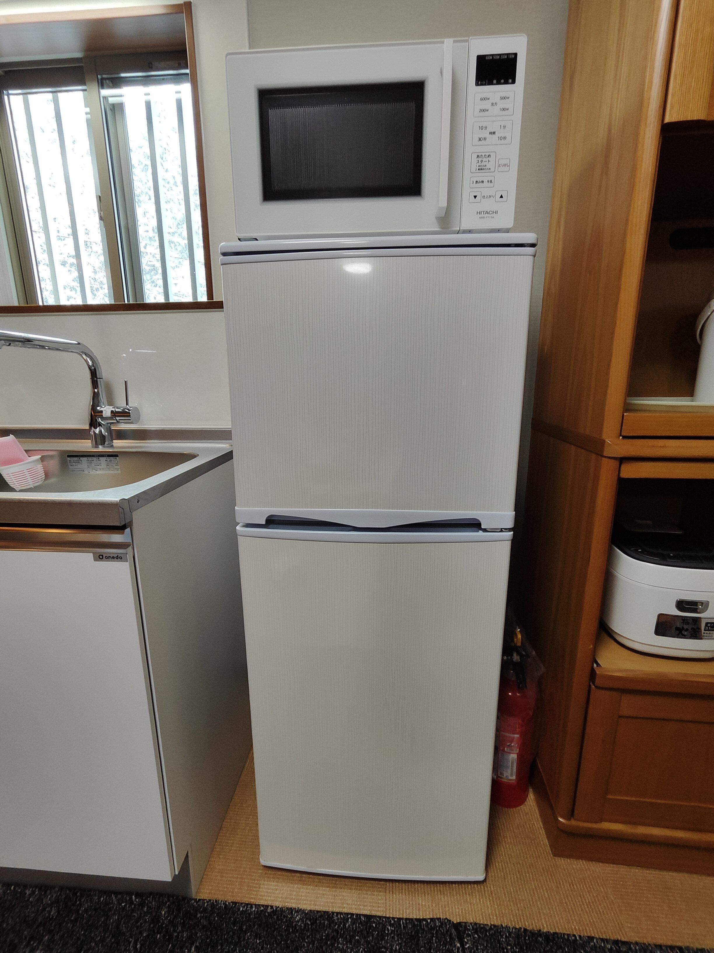 A compact kitchen with a built-in microwave and oven, a stainless steel sink, and a wooden cabinet.
