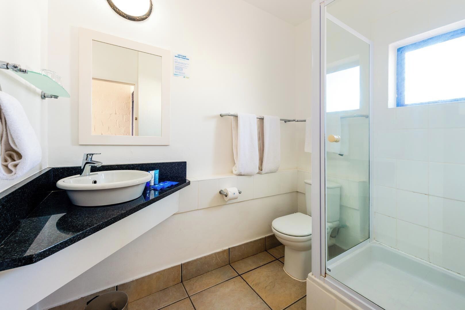 A modern bathroom with a sink, toilet, and glass shower enclosure.