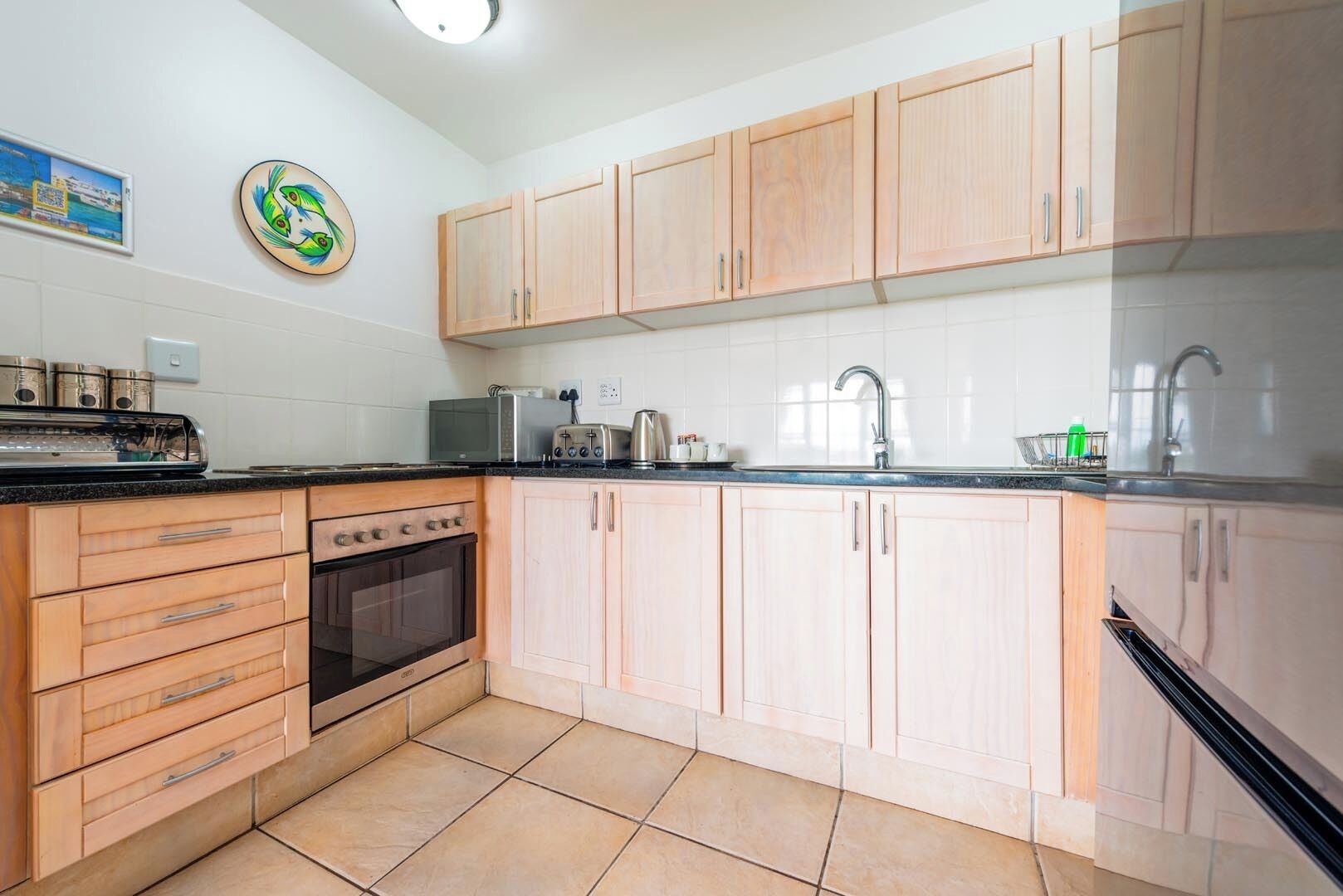 Une cuisine avec des meubles de rangement en bois, une cuisinière, un évier et un grille-pain.