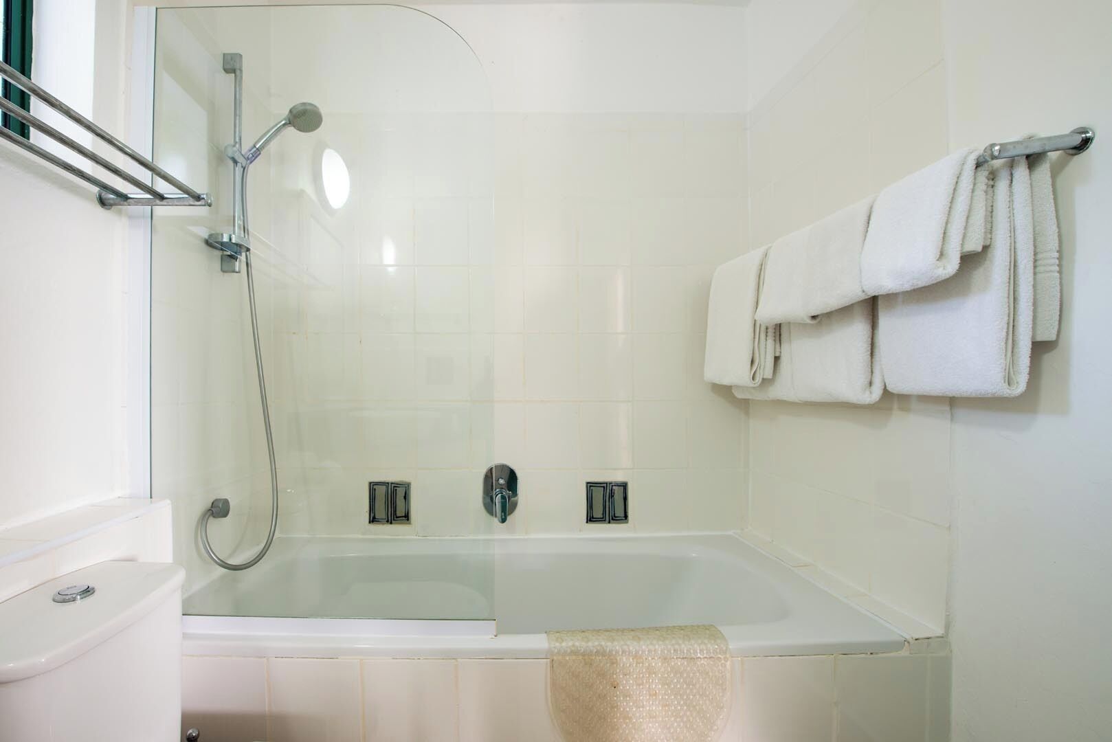 A bathroom with a glass-enclosed shower, a bathtub, and a towel rack with towels.