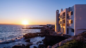 Un edificio costero con varios balcones que dan al mar al atardecer.