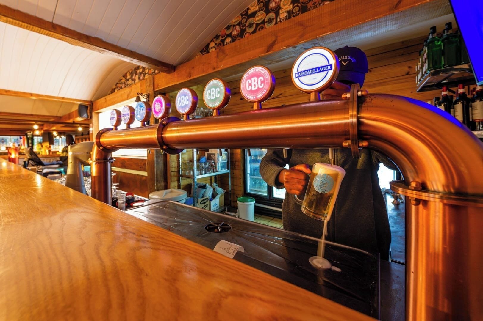 A bar with copper pipes and beer taps labeled with various brands.
