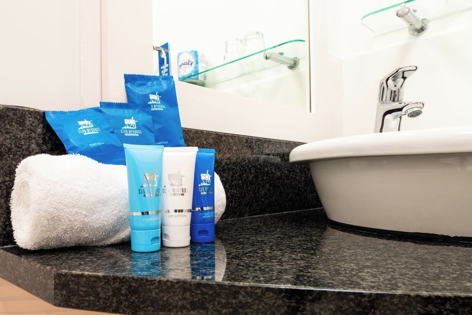 Ein Badezimmer mit einem weißen Waschbecken, einer schwarzen Arbeitsplatte und Pflegeprodukten, darunter Duschseife, Badeschaum und Lotion.