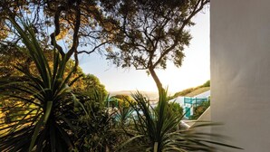 Un balcón con plantas tropicales, una piscina y vistas a un paisaje costero.