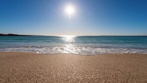 Una playa con cielo despejado y luz del sol reflejándose en el agua.