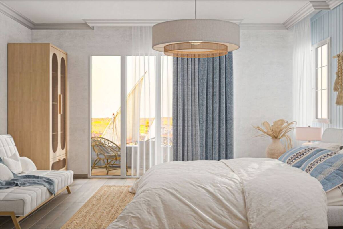 Ein Schlafzimmer mit einem großen Bett, einem Holzschrank, einem Sessel, einer Lampe und Blick durch eine Schiebetür auf einen Außenbereich.