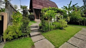Ein modernes Haus mit Satteldach, einer Steintreppe zum Eingang und einem gepflegten Garten mit unterschiedlichen Pflanzen und Rasenfläche.