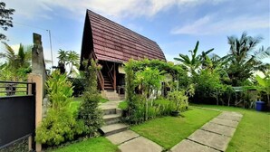 Ein Haus mit geneigtem Dach, umgeben von üppiger Vegetation und einem gepflegten Rasen.