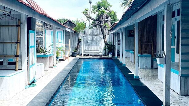 A swimming pool with a clear blue water surface, flanked by buildings with a traditional architectural style. - Kushak Bungalow Gili Trawangan (Gili Trawangan)