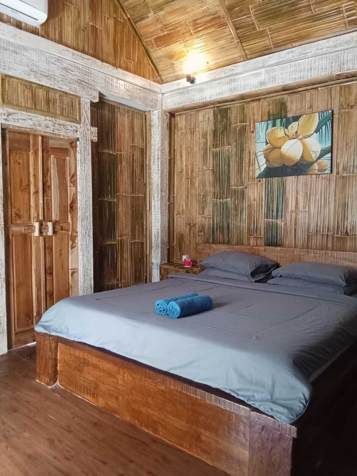Ein Zimmer aus Holz mit einem Bett, einer Tür und einer Wand mit einem Gemälde.