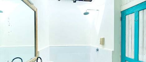 A bathroom with a white sink, wooden vanity, and a large mirror.