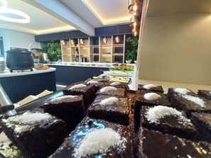 A buffet with various food items, including brownies topped with coconut. - Grand Belli Otel (Ankara)