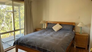 A bedroom with a bed, two bedside tables, a ceiling fan, and a large window with curtains. - 15% Off Weekly | Coastal-View Cypress Beach House (Island Beach)