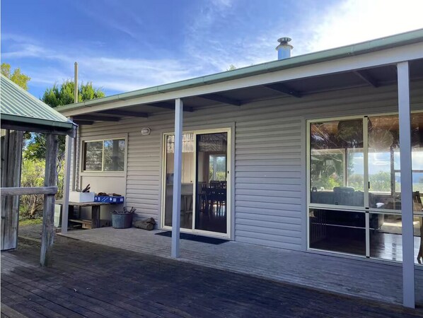 A single-story house with a covered porch, large sliding glass doors, and a deck.