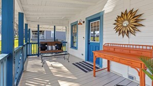 A covered porch with a bench, a table, and a decorative wall piece. - Welcome to The Schoolhouse – A charming cottage in historic Monticello, Florida. (Monticello)