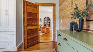 A room with a wooden door, a green dresser, and a mirror with a black vase. - Welcome to The Schoolhouse – A charming cottage in historic Monticello, Florida. (Monticello)