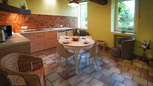 A kitchen with a dining table, chairs, and a window with a view of greenery.