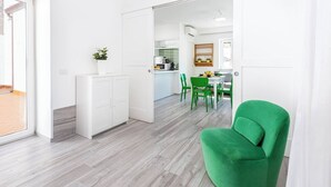 A modern kitchen with white cabinets, a dining area with green chairs, and a bright, airy space with a wooden floor. - Sorrento Villa With Pool And Amazing Views (Sorrento)