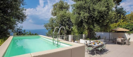 Een seizoensgebonden buitenzwembad en ligstoelen