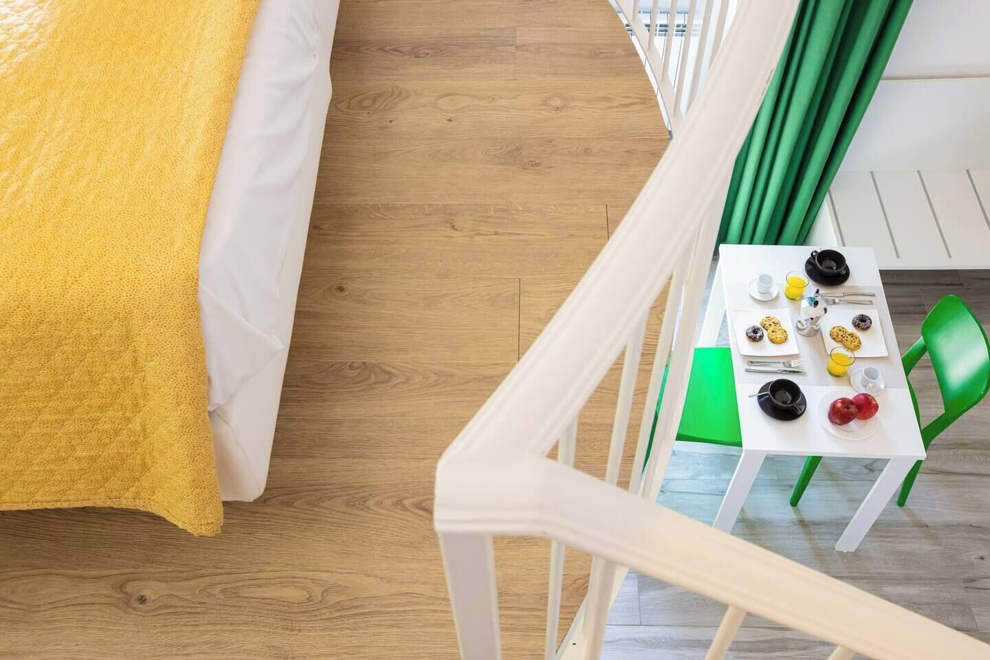 Ein Zimmer mit einem Bett, einem Esstisch mit Frühstücksgebäck und einem grünen Stuhl.
