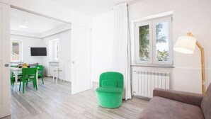 A modern living room with a green chair, a brown sofa, and a window with curtains. - Sorrento Villa With Pool And Amazing Views (Sorrento)