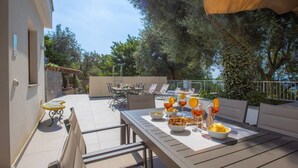 An outdoor patio with a dining table set for two, surrounded by lounge chairs and a large umbrella. - Sorrento Villa With Pool And Amazing Views (Sorrento)