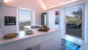A modern kitchen with a large island, built-in oven, and a view of the countryside. - Villa Breathtaking View Near Nerano (Massa Lubrense)