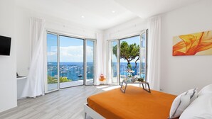 A modern bedroom with a large bed, a view of the sea, and a balcony with a table and chair. - Villa By The Beach With Sea-View And Luxury Amenities (Massa Lubrense)