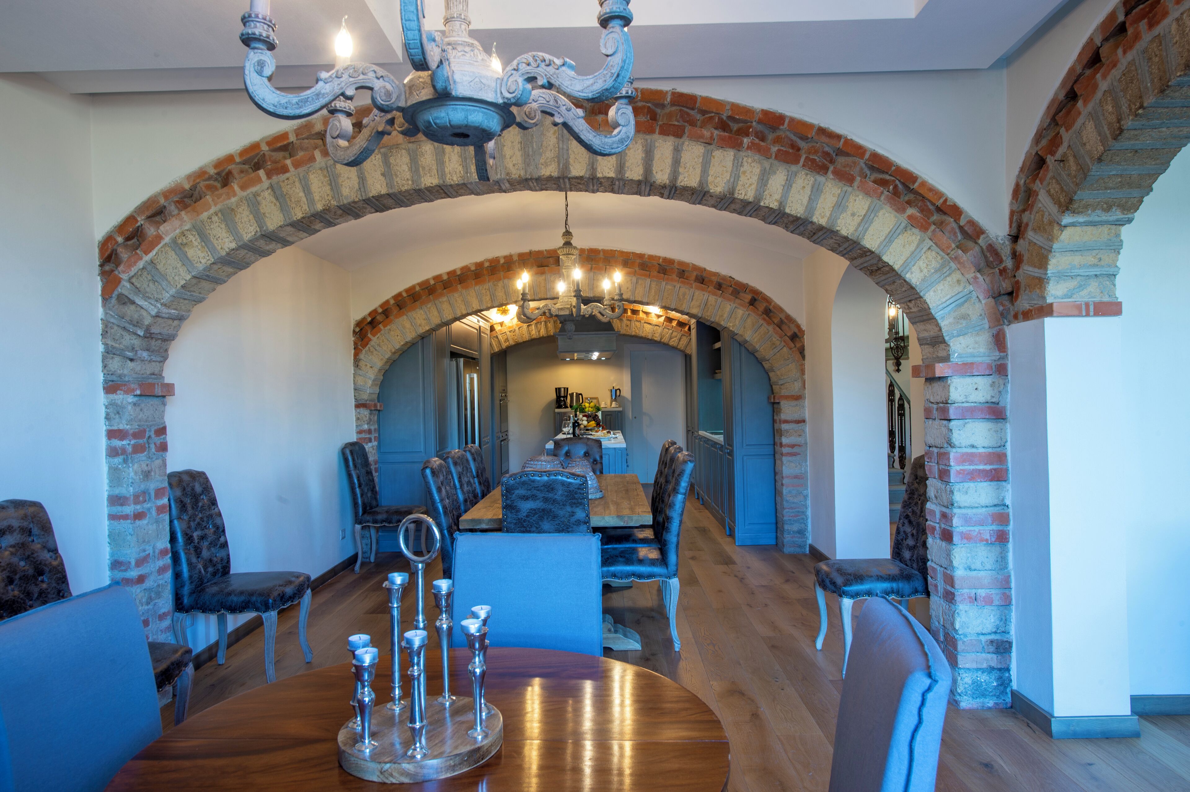 A dining area with a long wooden table, blue upholstered chairs, and a chandelier.