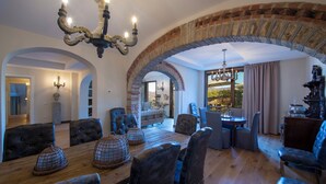 A dining area with a wooden table, upholstered chairs, and a chandelier. - Villa Chianti With Infinity Pool And Vineyard View (Greve in Chianti)