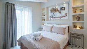 Ein Hotelzimmer mit einem großen Bett, einem Bild an der Wand und Regalen mit Dekoration.