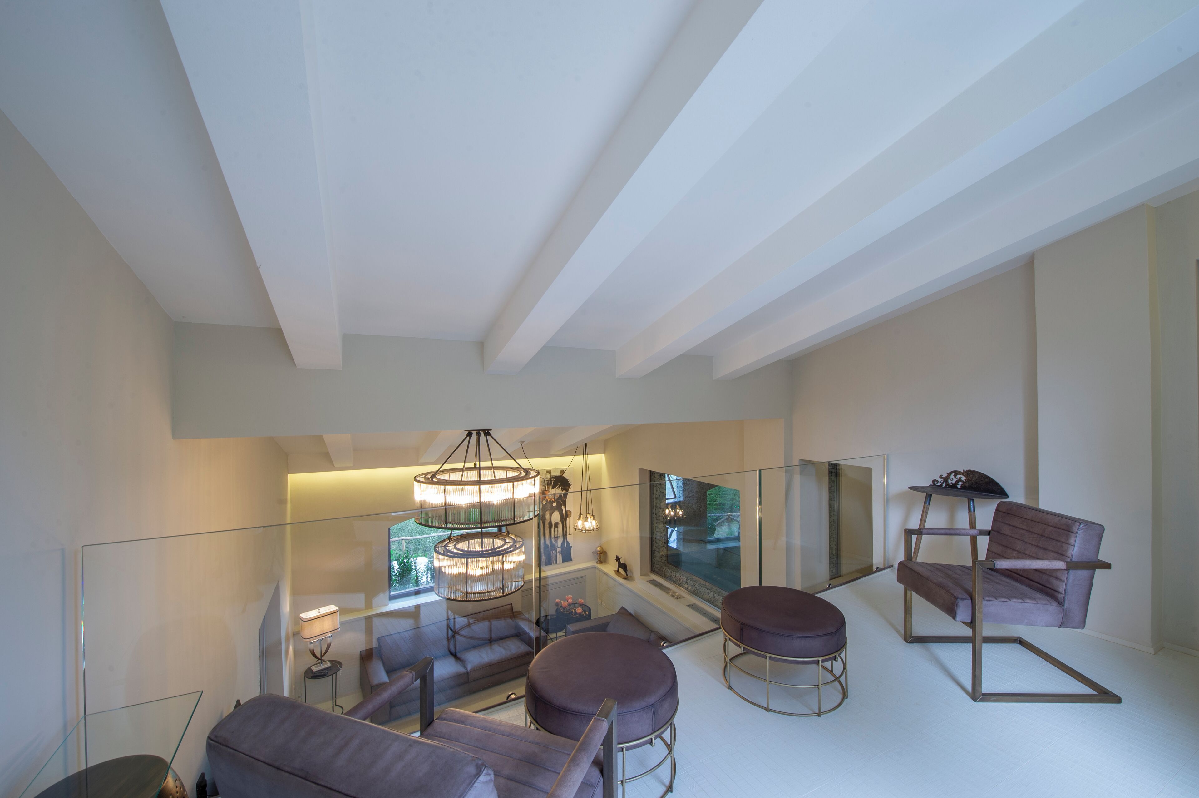 Una sala de estar moderna con una escalera de cristal, una mesa redonda y una zona de estar acogedora.