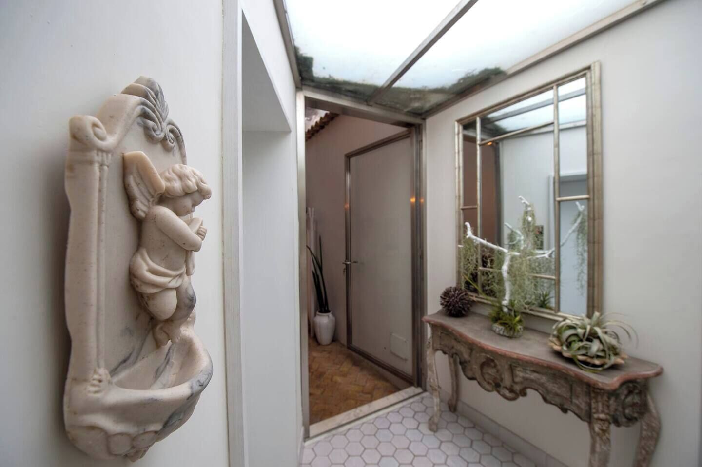 A hallway with a decorative stone relief, a mirror, and a console table with plants.