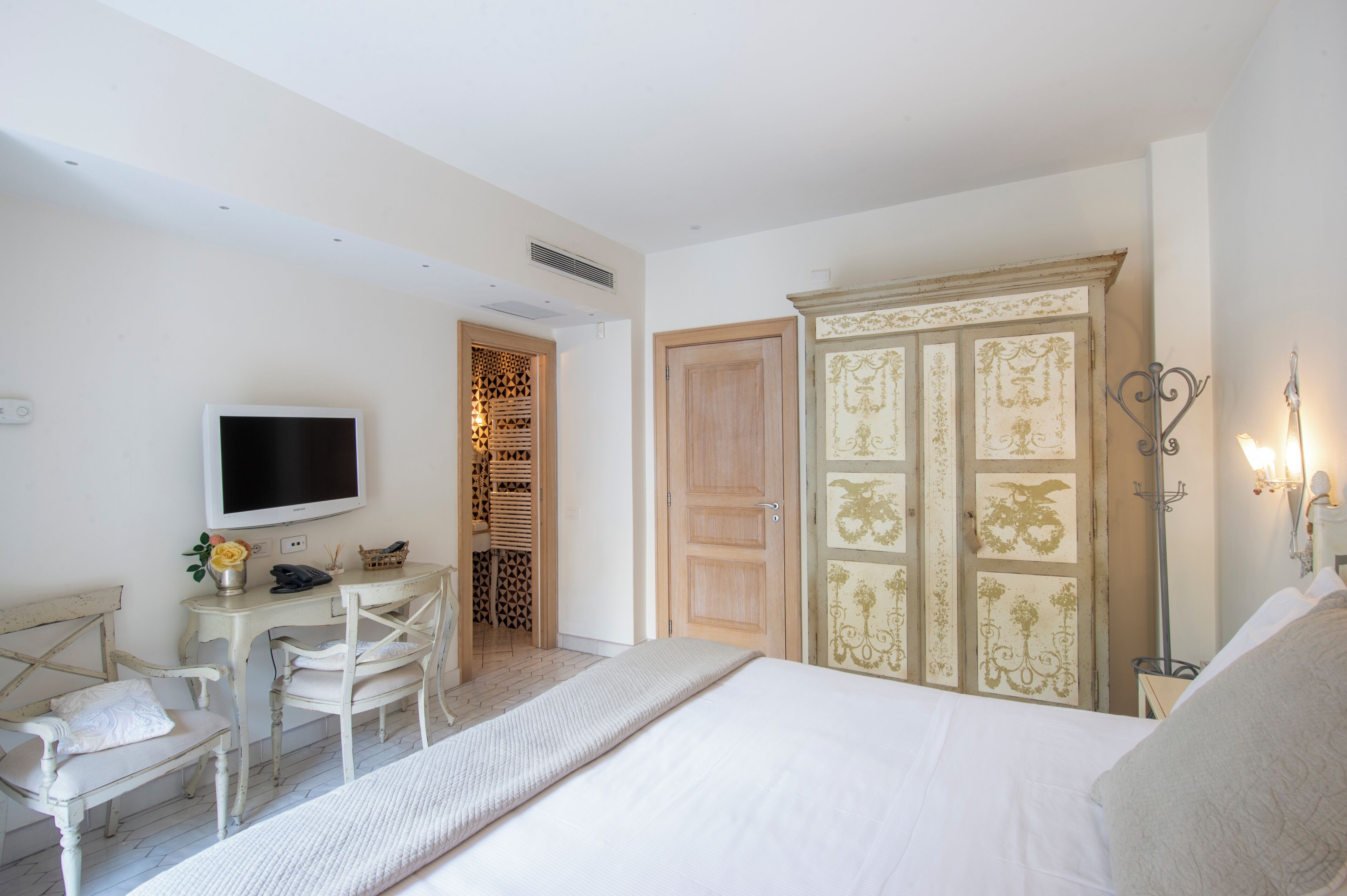 Een slaapkamer met een bed, een bureau met stoel, een televisie en een kledingkast.