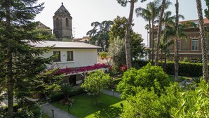 A building with a bell tower, surrounded by lush greenery and palm trees.