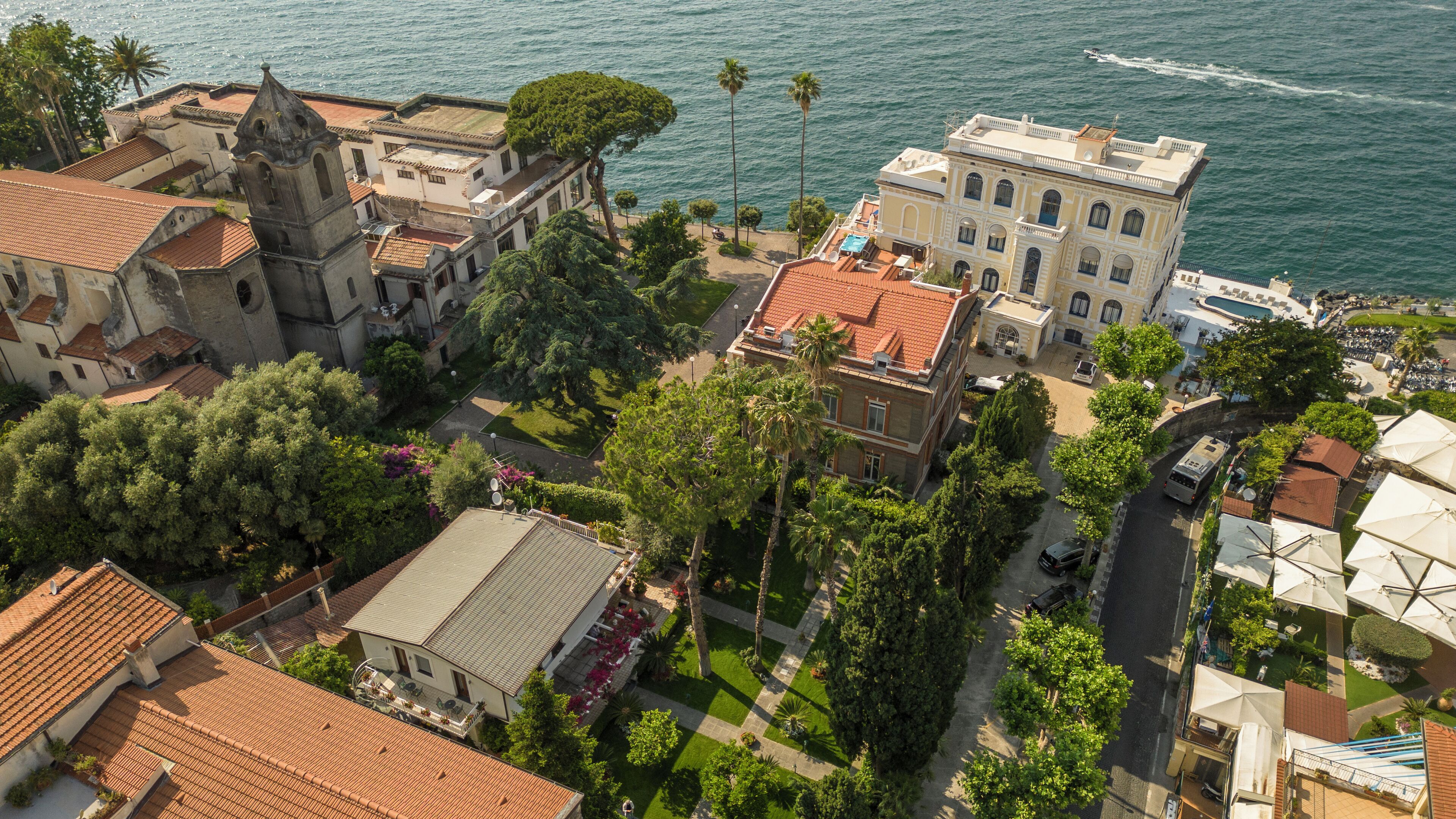 Vista aérea de un pueblo costero con edificios históricos, una iglesia y una zona frente a la playa.