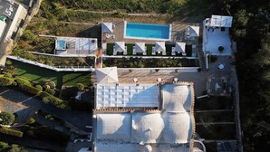 Vista aerea di un resort con piscina, numerosi lettini e un'area esterna coperta.