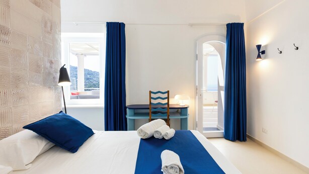 Una camera d'albergo con un letto, una scrivania, una sedia e vista sull'esterno.