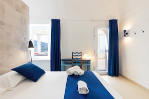 A hotel room with a bed, a desk, a chair, and a view of the outdoors. - Elegant Villa In Anacapri | Infinity Pool & Design (Anacapri)