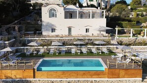 Un edificio di due piani con piscina e lettini.