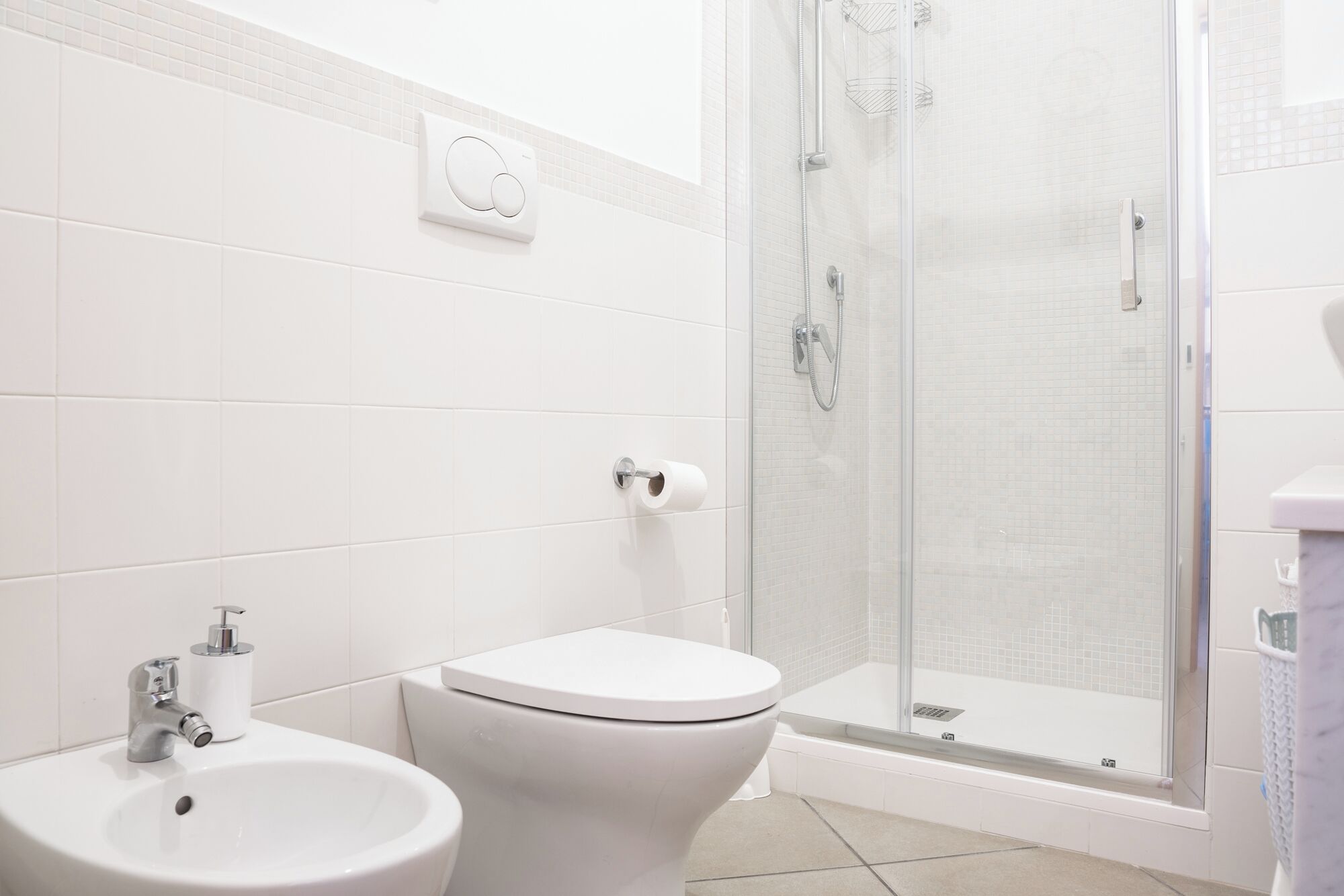Une salle de bain équipée de toilettes, d’un bidet et d’une douche à parois de verre.
