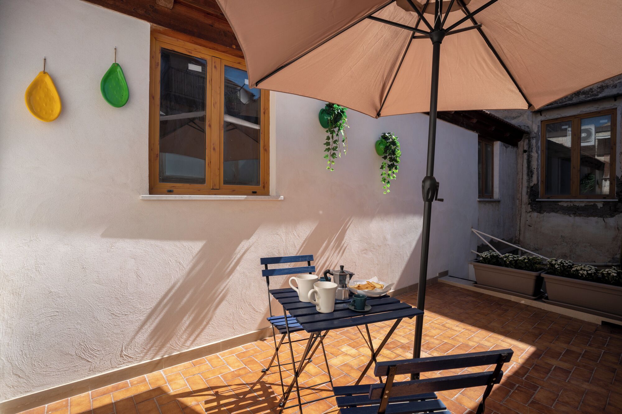 Um pátio com mesa, cadeiras e um guarda-sol.