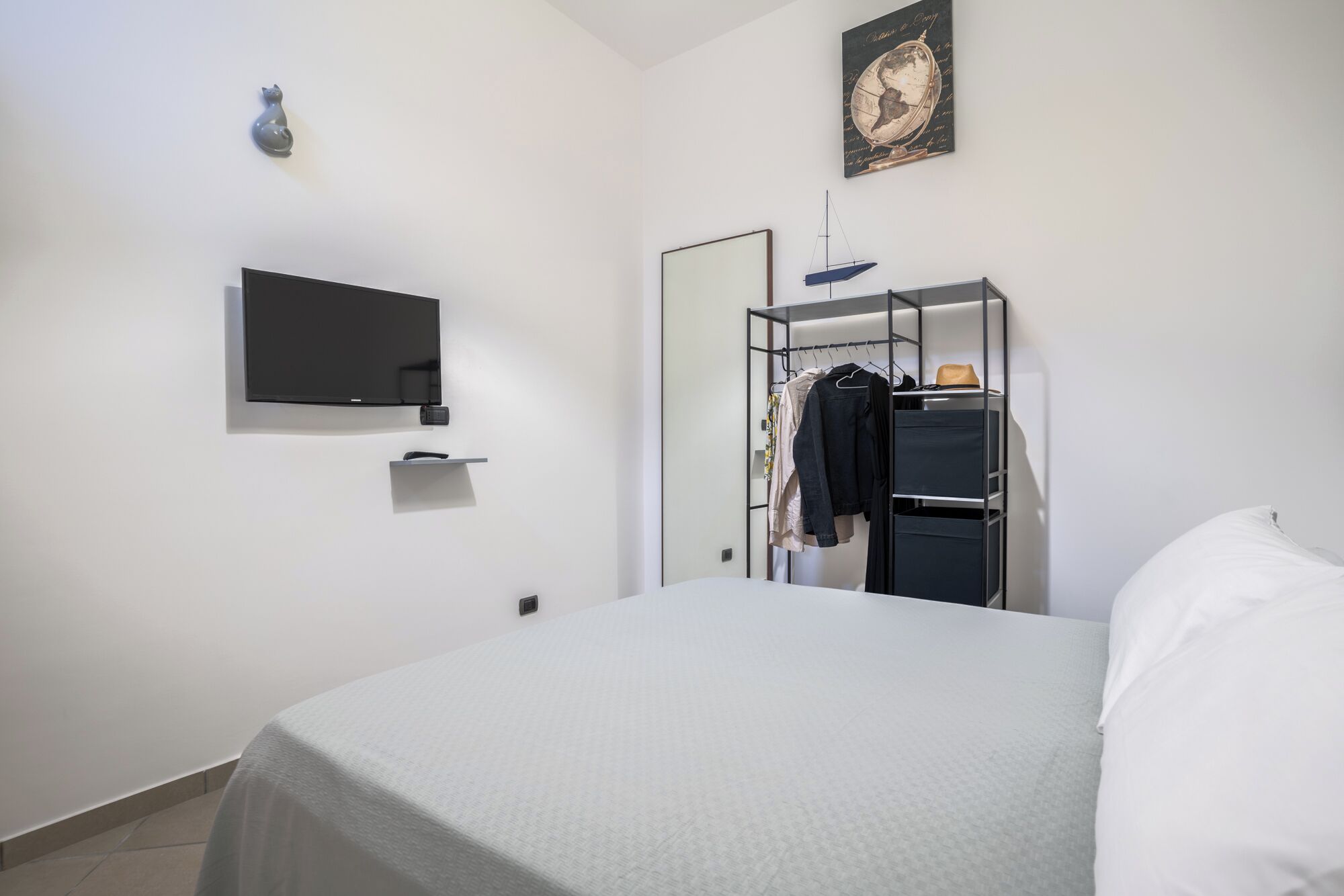Une chambre à coucher avec un lit, un téléviseur fixé au mur, une armoire et un globe décoratif.