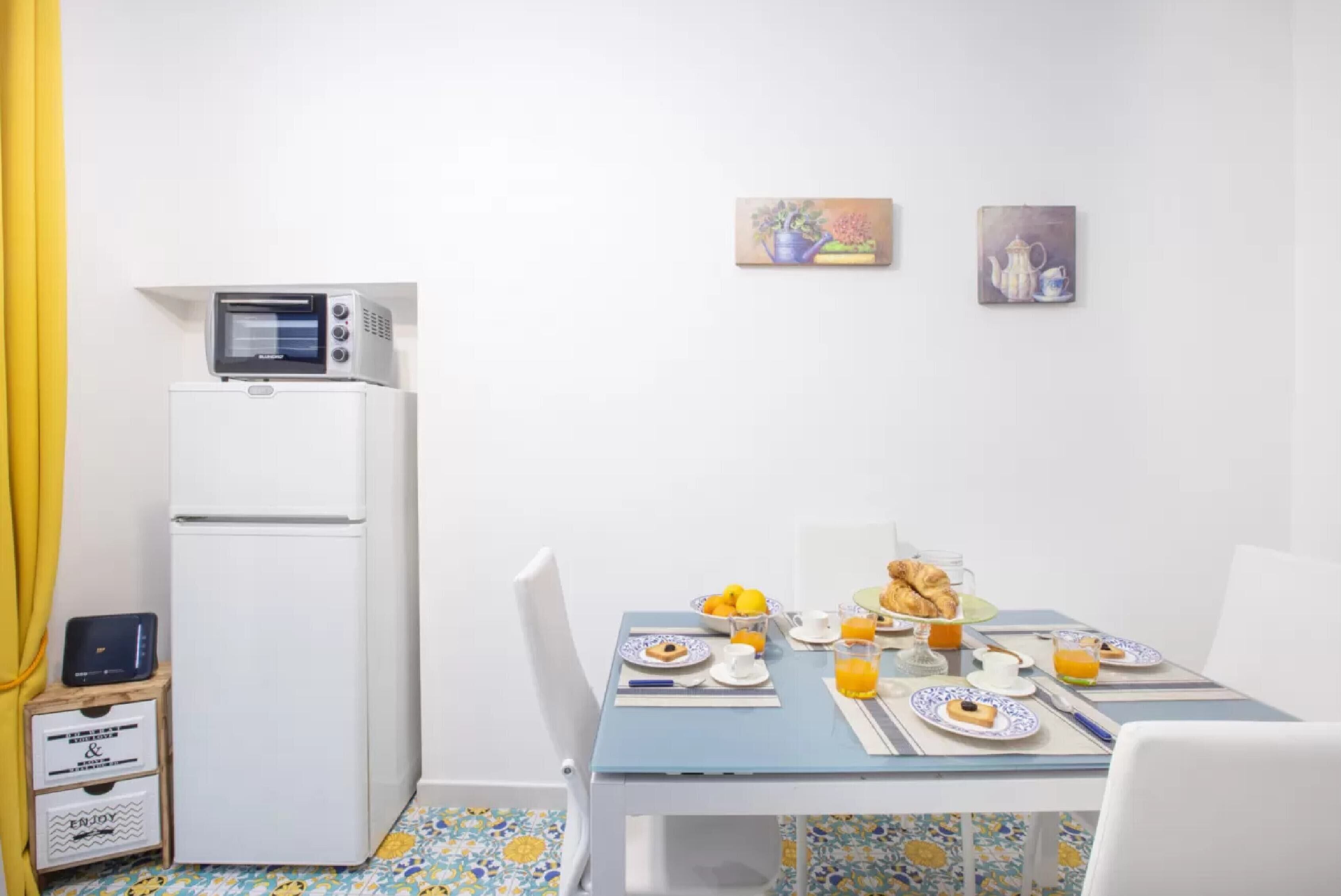 A dining area with a table set for breakfast, a microwave, and a refrigerator.