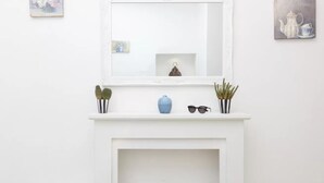 A white fireplace with a mirror above it, flanked by small potted plants and a blue vase. - Brezza Marina-Authentic Sorrento Flat By The Beach (Sorrento)