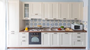 Une cuisine avec des meubles blancs, un four à micro-ondes, une cuisinière et un évier.