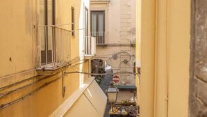 A narrow alleyway with yellow buildings, a balcony with a railing, and a small table with items on it. - Cosy House Under The Arches In Sorrento Old Town (Sorrento)