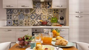A breakfast setting with a table, plates of food, a pitcher of orange juice, and a bowl of strawberries. - Cosy House Under The Arches In Sorrento Old Town (Sorrento)