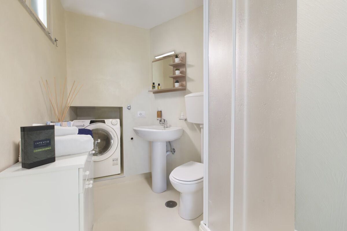 Un baño pequeño con lavadora, lavamanos e inodoro.